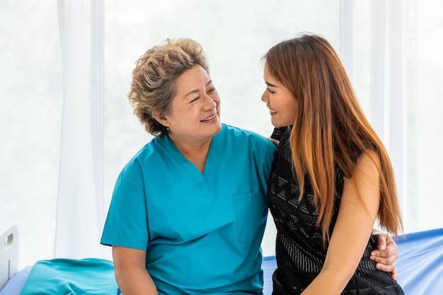 Молодая азиатская дочь навещает пожилую пожилую женщину-пациентку в больнице, чтобы поддержать и мотивировать здравоохранение и медицинскую концепцию