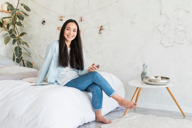 Free photo young asian female sitting on bed