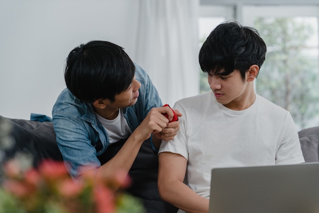 젊은 아시아 게이 커플 현대 가정에서 제안, 사춘기 한국 LGBTQ 남자 행복 미소 집에서 거실에서 결혼 반지 결혼 반지를 제안하고 결혼하면서 낭만적 인 시간이 있습니다.