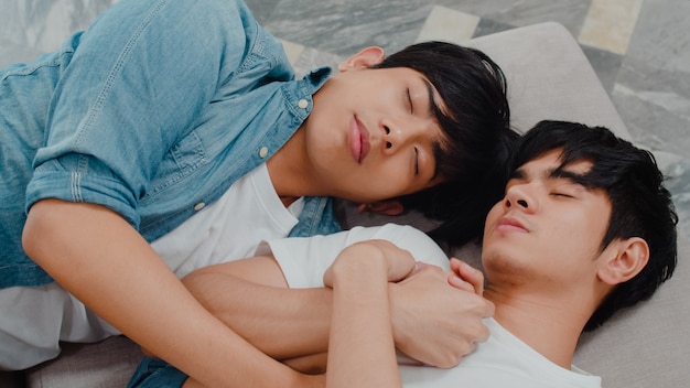 Young Asian gay couple sleep together at home. Teen korean LGBTQ+ men happy relax rest lying on bed in bedroom at house in the morning.