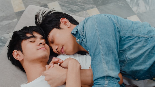 Young Asian gay couple sleep together at home. Teen korean LGBTQ+ men happy relax rest lying on bed in bedroom at house in the morning.