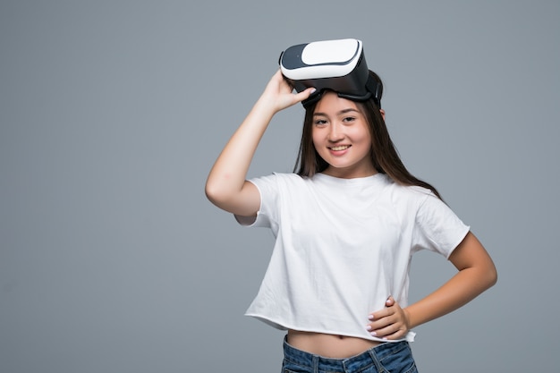 VRを見て若いアジアの女の子と灰色の背景に空気に手を触れる