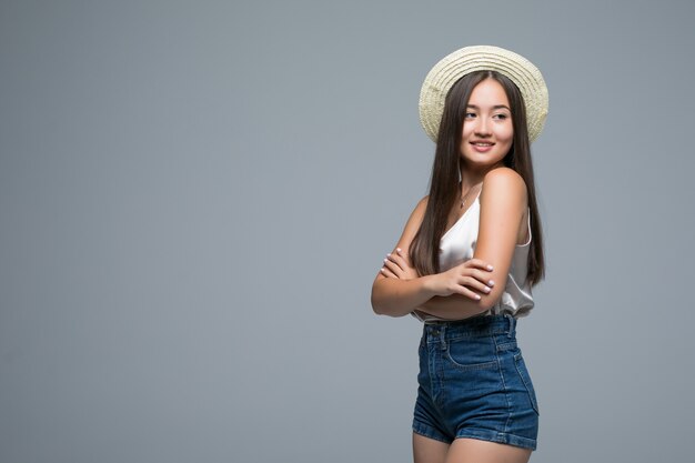 Young asian girl with straw hat isolated on gray background