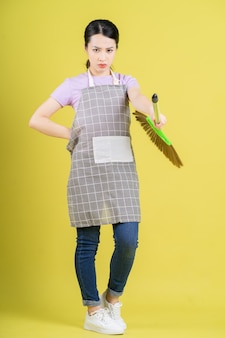 Young asian housewife posing on yellow background