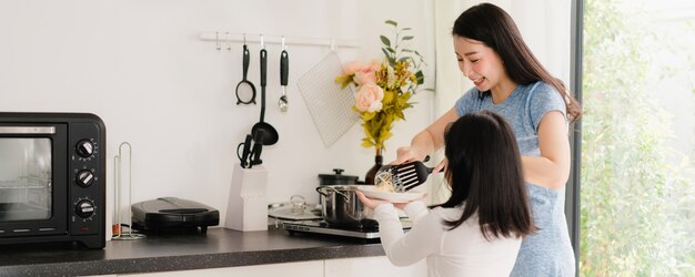 젊은 아시아 일본 엄마와 딸 집에서 요리. 라이프 스타일 여성 아침에 집에서 현대 부엌에서 아침 식사를 위해 파스타와 스파게티를 함께 만드는 행복.