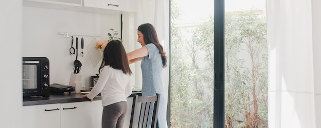 Young Asian Japanese Mom and Daughter cooking at home. Lifestyle women happy making pasta and spaghetti together for breakfast meal in modern kitchen at house in the morning .