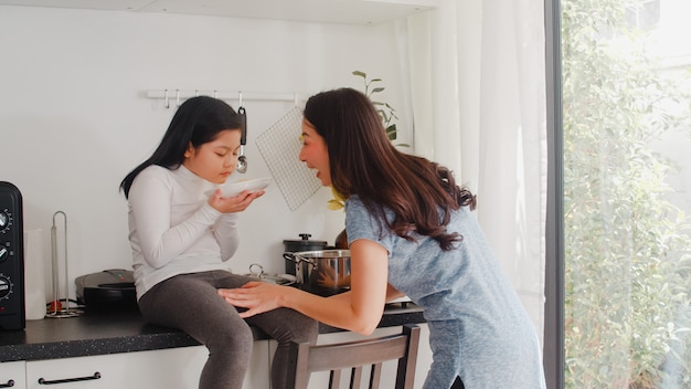 Young Asian Japanese Mom and Daughter cooking at home. Lifestyle women happy making pasta and spaghetti together for breakfast meal in modern kitchen at house in the morning .