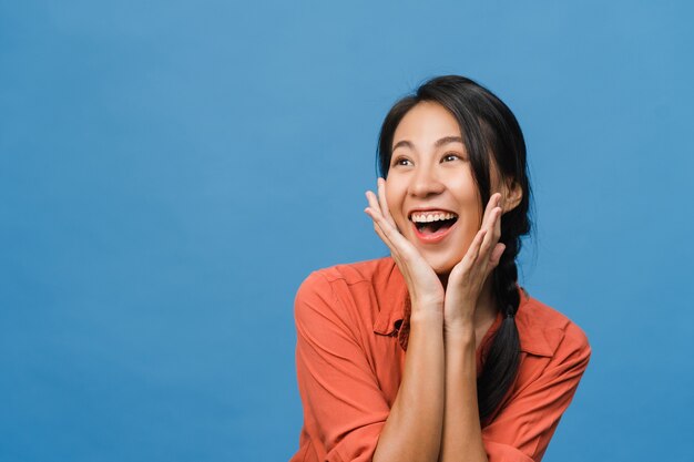 Young Asian lady feel happiness with positive expression, joyful surprise funky, dressed in casual cloth isolated on blue wall. Happy adorable glad woman rejoices success. Facial expression.