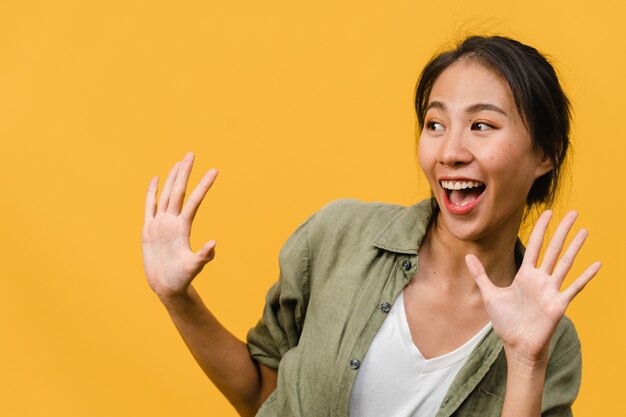 Young Asian lady feel happiness with positive expression, joyful surprise funky, dressed in casual cloth isolated on yellow wall. Happy adorable glad woman rejoices success. Facial expression.