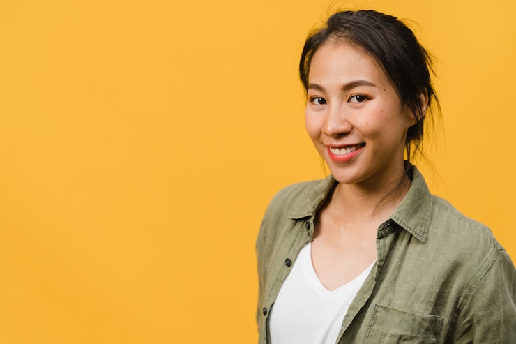 Free Photo young asian lady with positive expression, smile broadly, dressed in casual clothing  over yellow wall. happy adorable glad woman rejoices success. facial expression concept.