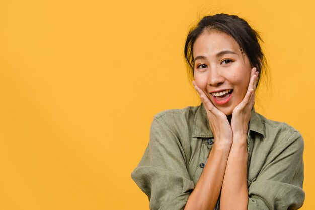 Young Asian lady with positive expression, smile broadly, dressed in casual clothing  over yellow wall. Happy adorable glad woman rejoices success. Facial expression concept.