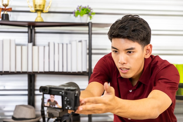 Free photo young asian male online merchant blogger prepare and set up camera for live video and review to sell product social media and online influencer concept