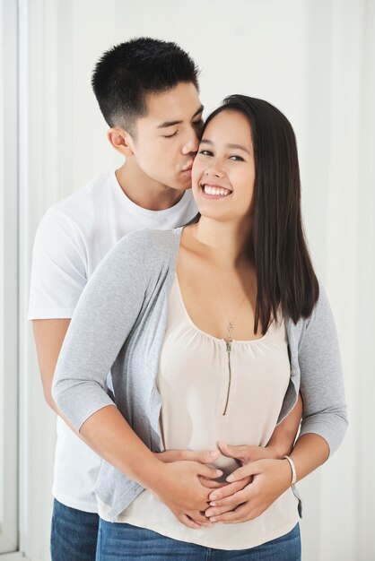 Young Asian man hugging and kissing girlfriend on cheek