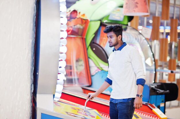 Молодой азиатский человек играет на игровых автоматах колеса удачи, чтобы попытаться выиграть в лотерею с большим призом