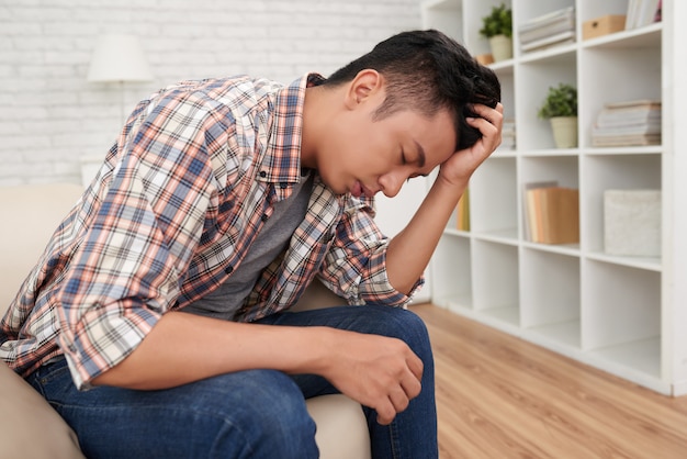 Young asian man sufferng headache horizontal side view shot