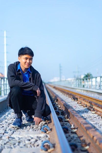 Young Asian man with casual clothing crouched on a railway in Ho Chi Minh City, Vietnam