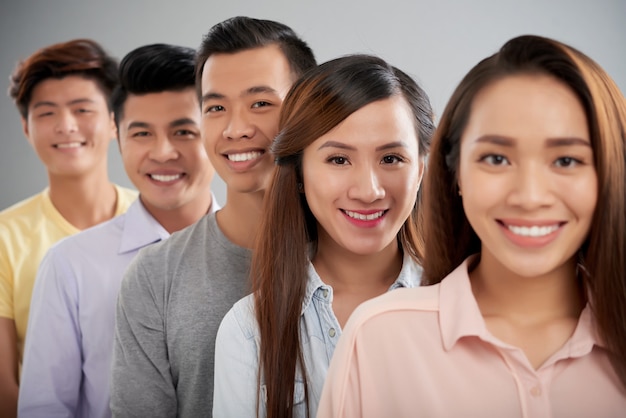 Young Asian people facing camera standing one by one in a row smiling 