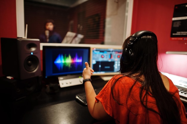 Free photo young asian singer man with microphone recording song in record music studio with sound producer