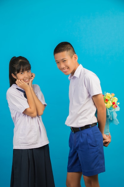 Молодые азиатские студенты и азиатские студенты стоят вместе на синем.