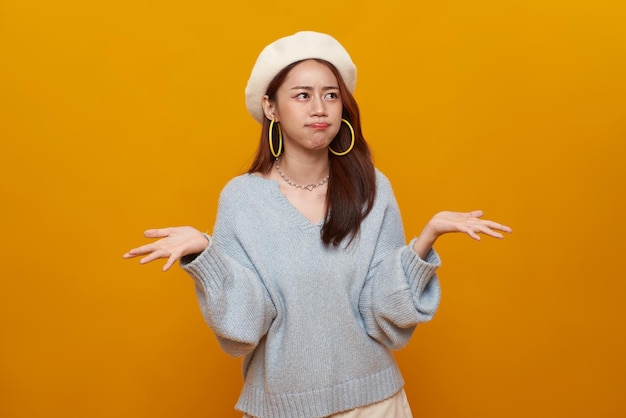 Free photo young asian teenage girl standing with raised hands and indignant face asking why annoyed by problem