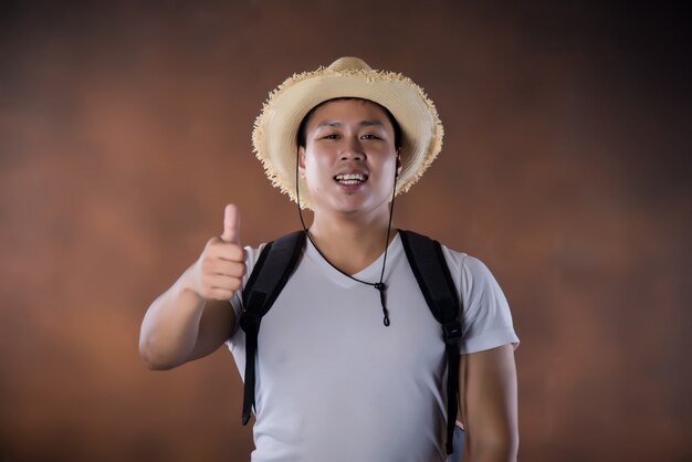 Young Asian traveling backpacker with bag and hat 