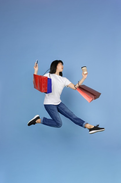 Молодая азиатская женщина на синем, шоппинг