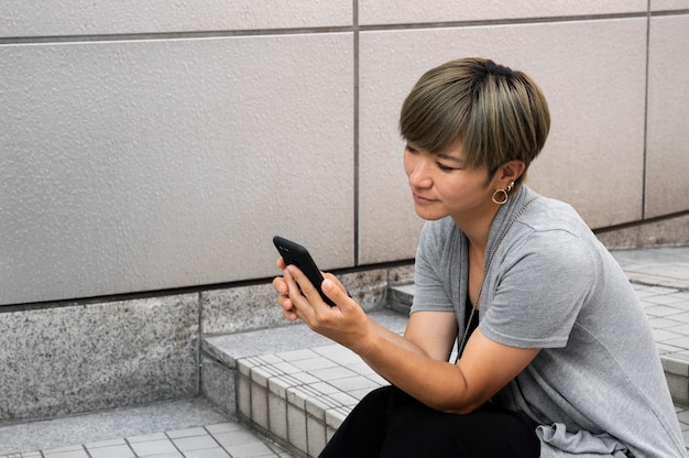 屋外で彼女の電話をチェックする若いアジアの女性