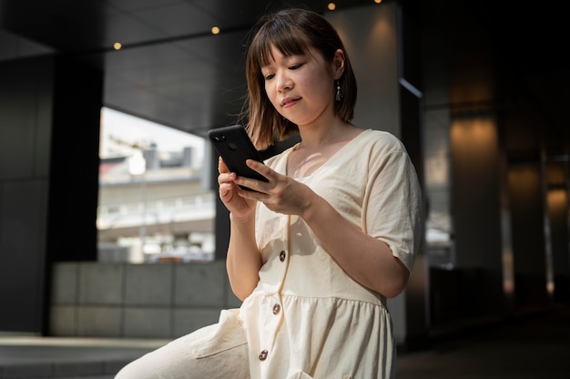 Молодая азиатская женщина, проверяющая ее телефон