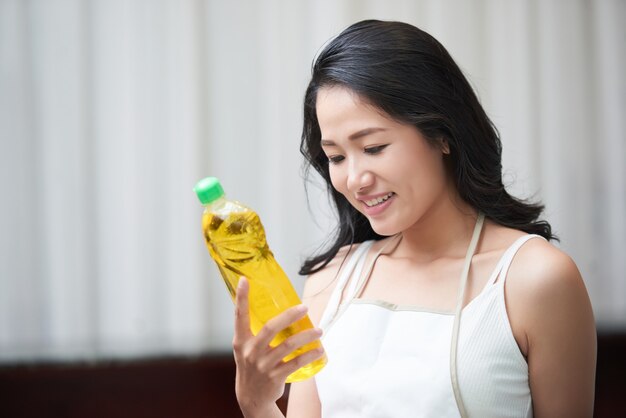 洗剤のボトルを探索する若いアジア女性