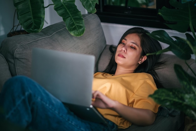 Free photo young asian woman freelancer working at night in living room while work at home mental health health care concept