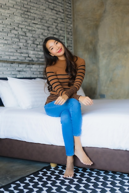 Free photo young asian woman happy smile relax on bed in bedroom