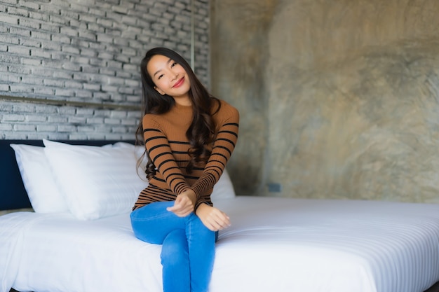 若いアジア女性の幸せな笑顔が寝室のベッドでリラックスします。