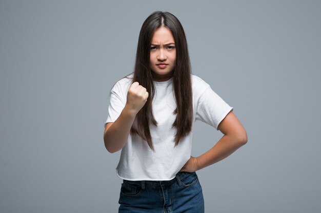 Young asian woman hold fist up on gray background