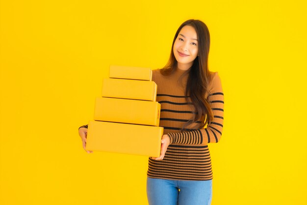 young asian woman holding cardboard box in her hand on yellow