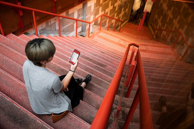 Молодая азиатская женщина, смотрящая на приложение на своем телефоне
