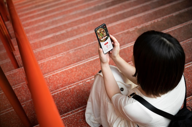 Foto gratuita giovane donna asiatica che guarda un'app sul suo telefono