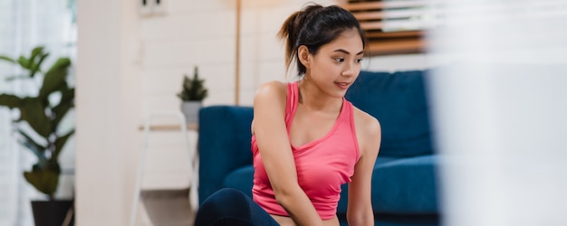 Young Asian woman practicing yoga in living room. 