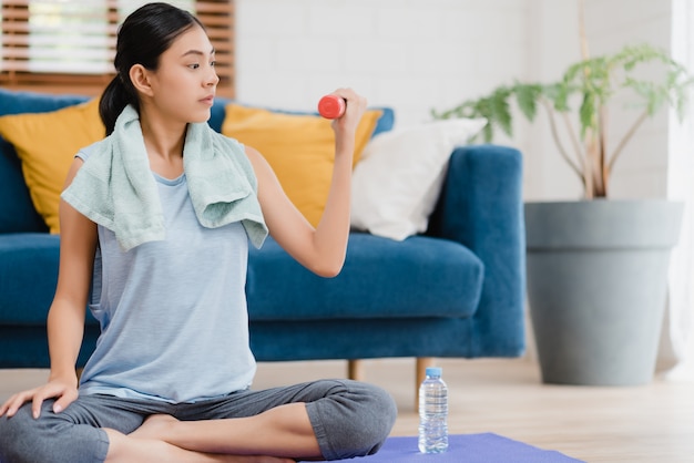 Young Asian woman practicing yoga in living room. 
