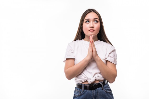 Young asian woman praying isolated on white wall