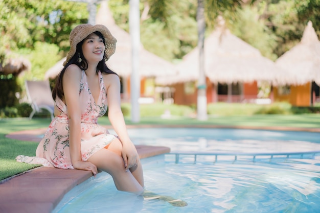 Young Asian woman relax near swimming pool in hotel, Beautiful female happy relax near sea.