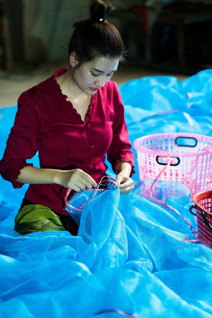 Foto gratuita giovane donna asiatica che cuce la rete al villaggio di pescatori