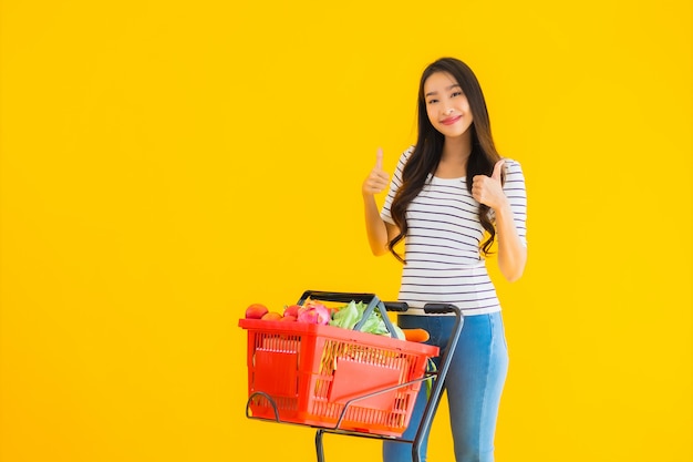 スーパーマーケットとカートから食料品を買い物若いアジア女性