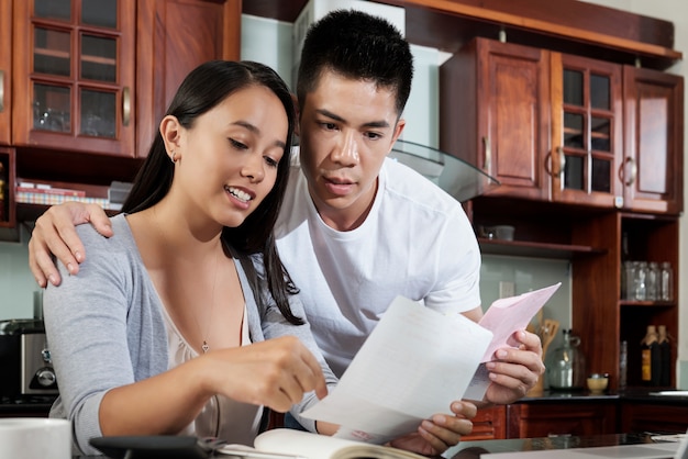 Young asian woman showing bills to her husband