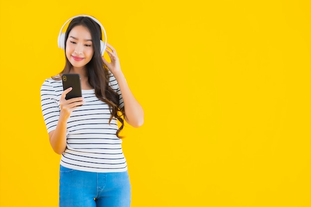若いアジアの女性は、ヘッドフォンでスマートな携帯電話を使用します。