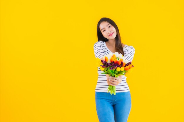 カラフルな花を持つ若いアジア女性