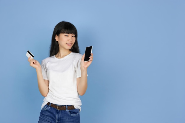 신용 카드와 스마트폰을 가진 젊은 아시아 여성