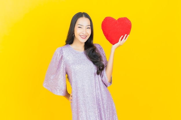 Free photo young asian woman with heart pillow