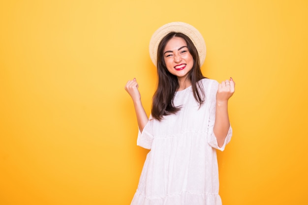 Free photo young asian woman with winning gesture isolated on yellow wall