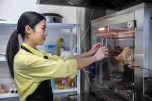 Free photo young asian woman working in the kitchen and regulating ovens temperature