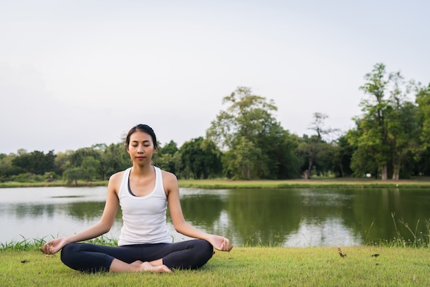 Young asian woman yoga outdoors keep calm and meditates while practicing yoga